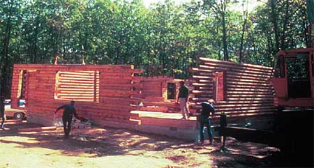Log wall being placed by crane.